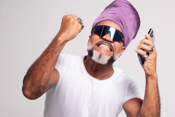 Fotografia colorida de Carlinhos Brown com uma blusa branca em parceria com Betsul