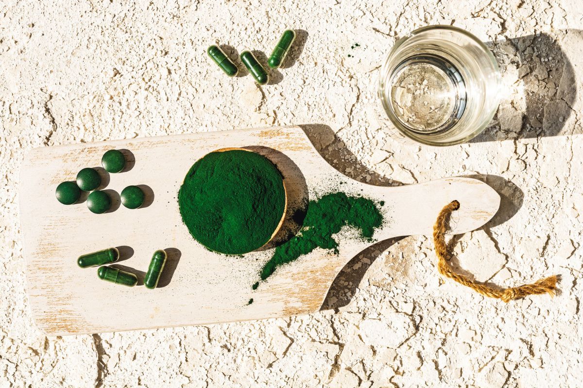 tábua com cápsulas e pó do suplemento natural spirulina
