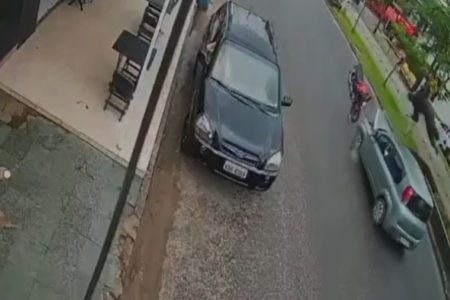 Imagem colorida mostra motociclista voando após atingir carro de frente em uma avenida no Guarujá, litoral de São Paulo - Metrópoles