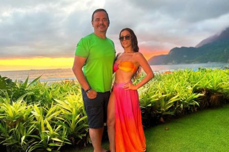 Carioca e Paola Machado em foto colorida. Eles estão na praia, ele com blusa verde - Metrópoles