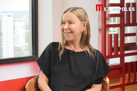 Mulher de blusa preta, sorrindo de perfil - Metrópoles