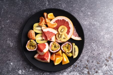 frutas em tons de laranja, amarelo e vermelho em um fundo escuro