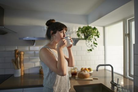 Foto colorida de uma mulher tomando café - Metrópoles