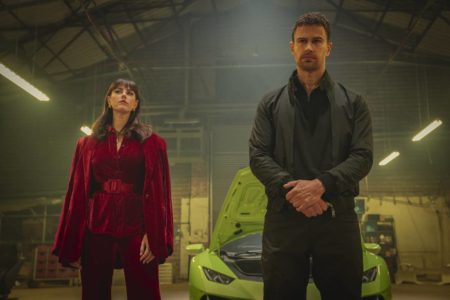 Uma mulher com roupa vermelha e um homem de terno em frente a um carro de luxo - Metrópoles
