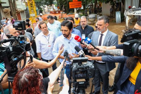 Imagem colorida mostra Ricardo Nunes, homem branco, de cabelo e barba pretos, de camisa clara e calça jeans, cercado por jornalistas, dando entrevistas em uma obra - Metrópoles