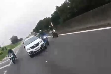 Print de imagem de vídeo em que carro Kwid branco ultrapassa uma moto na direita do carro em rodovia