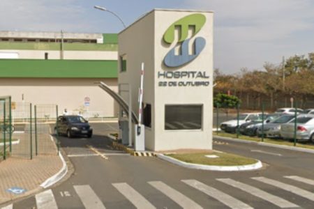 Imagem colorida da fachada do Hospital 22 de Outubro, na imagem também aparecem carros. Metrópoles