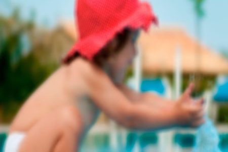 Imagem embaçada de criança sozinha na beira de piscina -