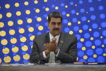 foto colorida de Nicolás Maduro sentado, de terno batendo palmas - metrópoles