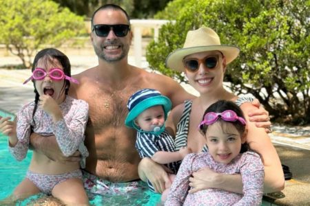 foto colorida de mulher e homem com bebe e duas meninas gemeas na piscina - metrópoles