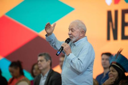 Imagem colorida do presidente Lula falando ao microfone - Metrópoles