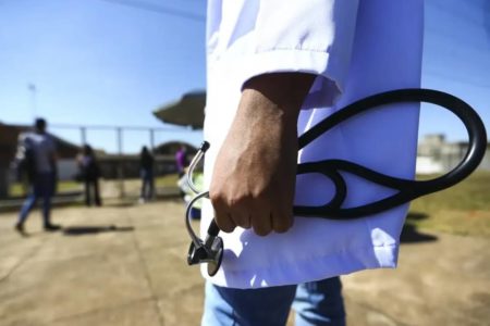 Foto colorida de mão masculina com equipamento médico e avental
