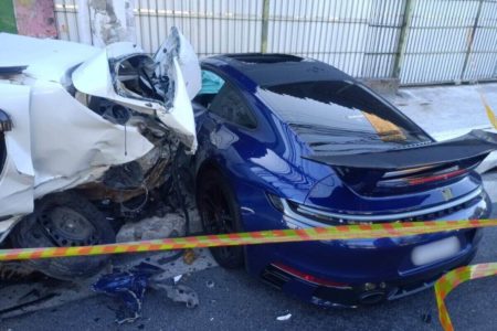 Em foto colorida, na esquerda, Renault Sandero branco com traseira destruída e, na direita, Porsche azul escuro com traseira intacta e fora de isolamento policial - Metrópoles