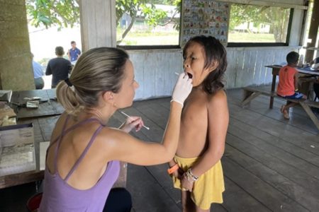 Foto colorida de criança Yanomami sendo atendida por pesquisadora da Fiocruz - Metrópoles