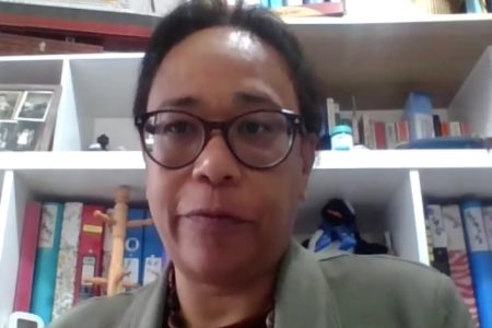 Foto de mulher com prateleira de livros ao fundo - Metrópoles