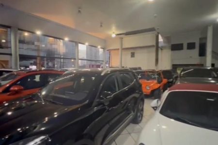 Foto colorida do interior de concessionária de veículos de luxo com luzes acesa - Metrópoles