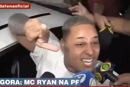 Na imagem colorida, homem aponta o dedo enquanto é abordado por microfones - Metrópoles