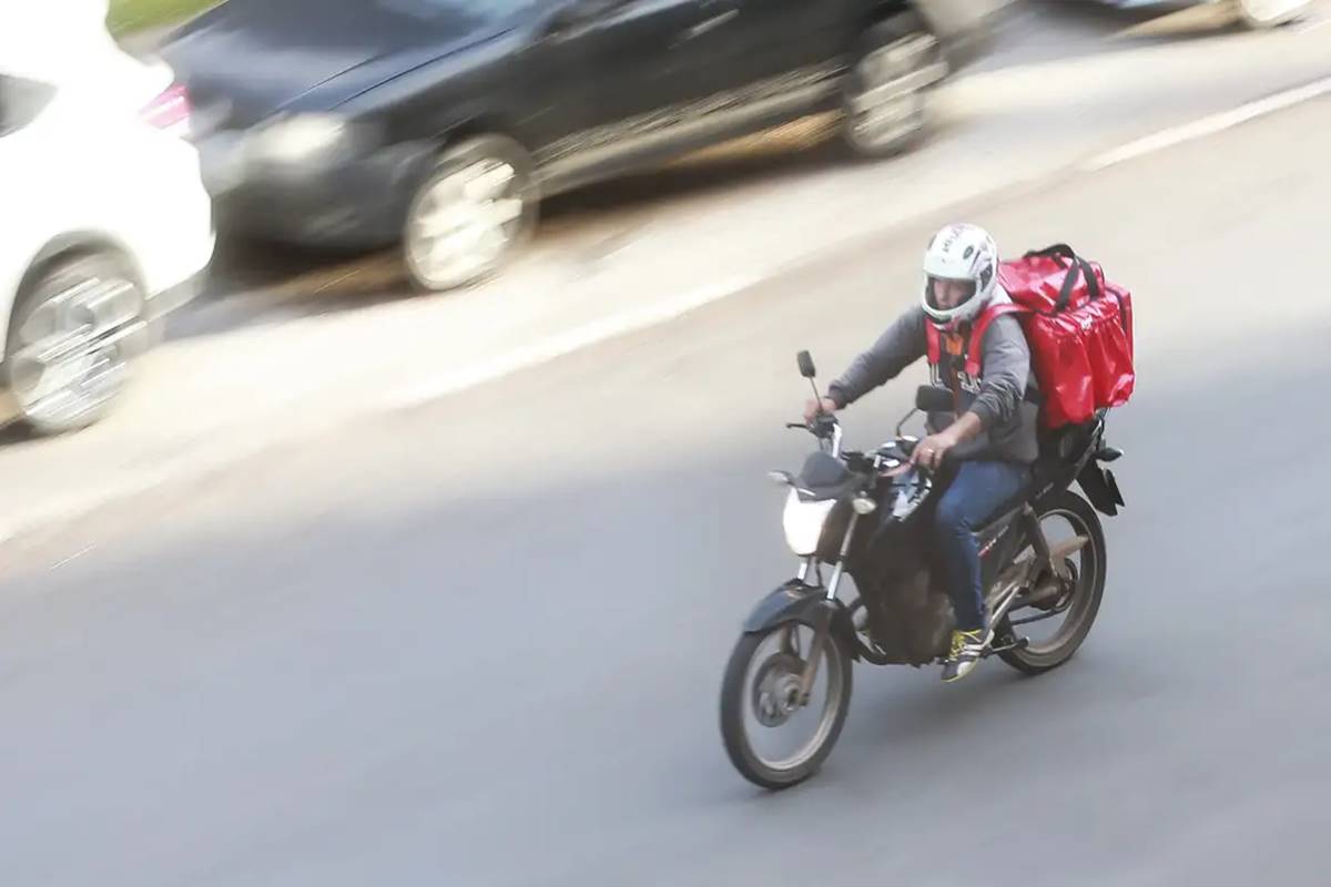 Foto colorida de motoboy na rua