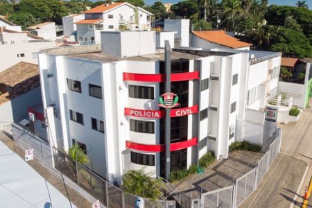 Prédio de quatro andares com paredes brancas escrito na fachada "Polícia Civil"