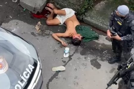Imagem mostra policial militar (PM) ao lado de homem baleado - Metrópoles