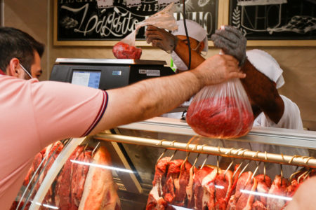 Acougueiro entrega sacola com carne bovina a cliente