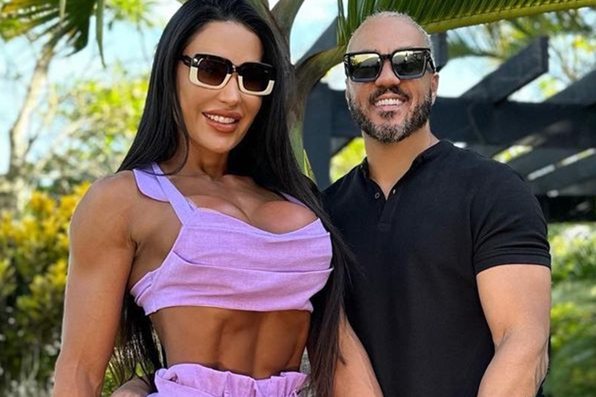 Gracyanne Barbosa e Belo posam juntos e sorridentes, usando óculos escuros - Metrópoles