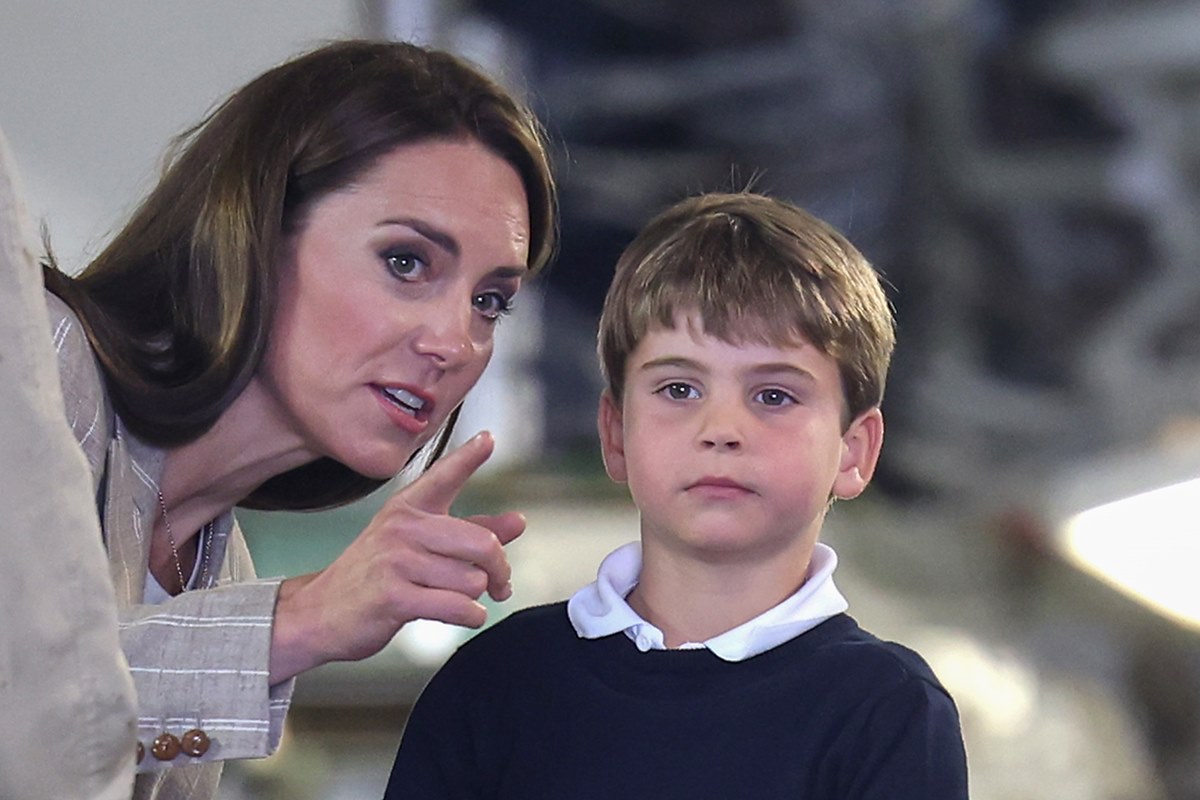 Foto colorida de mulher apontando para algo enquanto fala com menino - Metrópoles