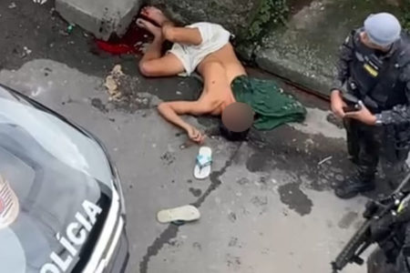 Imagem mostra policial militar (PM) ao lado de homem baleado - Metrópoles