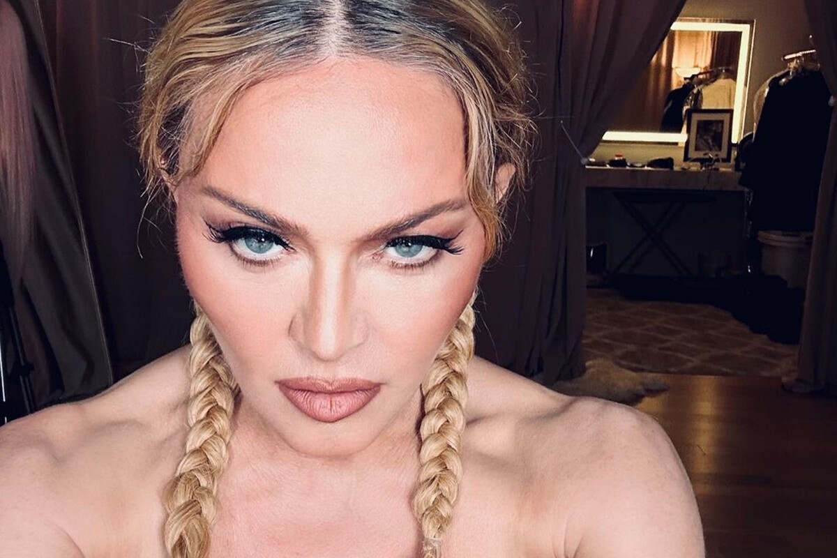 Madonna posa, séria, de blusa tomara que caia e tranças - Metrópoles