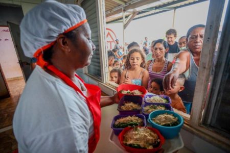 Merendeira distribuindo alimentos para crianças Brasil - Metrópoles