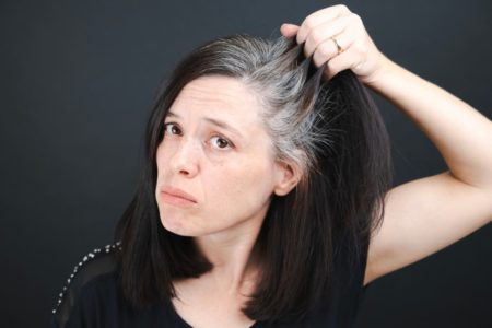 mulher de cabelo preto mostrando os fios brancos
