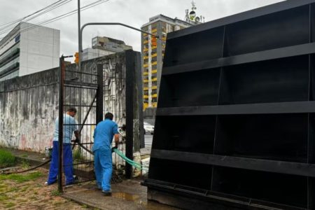 Foto colorida de trabalhadores da prefeitura fecham comportas de sistema de segurança para evitar inundação pelo Guaíba em Porto Alegre - Metrópoles