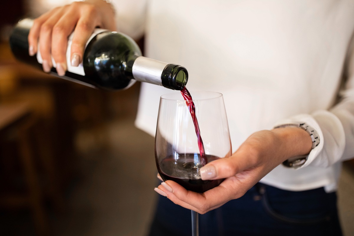 Foto de mulher colocando vinho dentro de uma taça - Metrópoles
