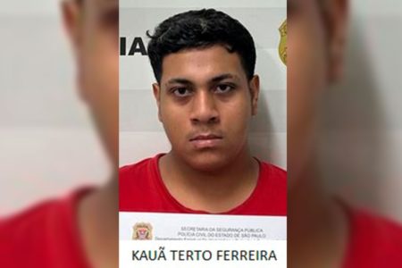 Imagem colorida de homem de camisa vermelha preso. Metrópoles