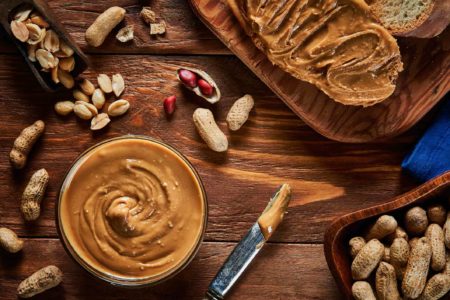 Foto de stock de Peanut butter scattered on a slice of bread on rustic background