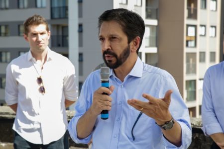 Imagem colorida mostra Ricardo Nunes, homem branco, de cabelo e barba pretos, falando ao microfone. Ele veste uma camisa azul de mangas dobradas - Metrópoles