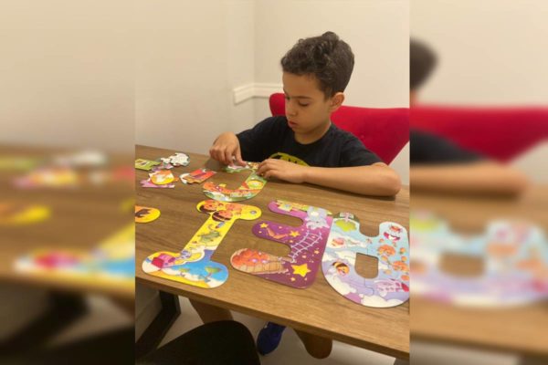 Foto colorida de menino com quebra-cabeça 
