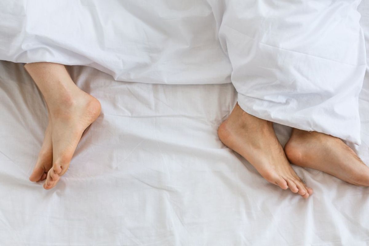 Pessoas deitadas na cama foto aparecendo somente o pé