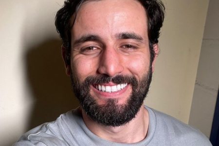 O ex-BBB Matteus Amaral posa, sorridente, com uma blusa cinza - Metrópoles