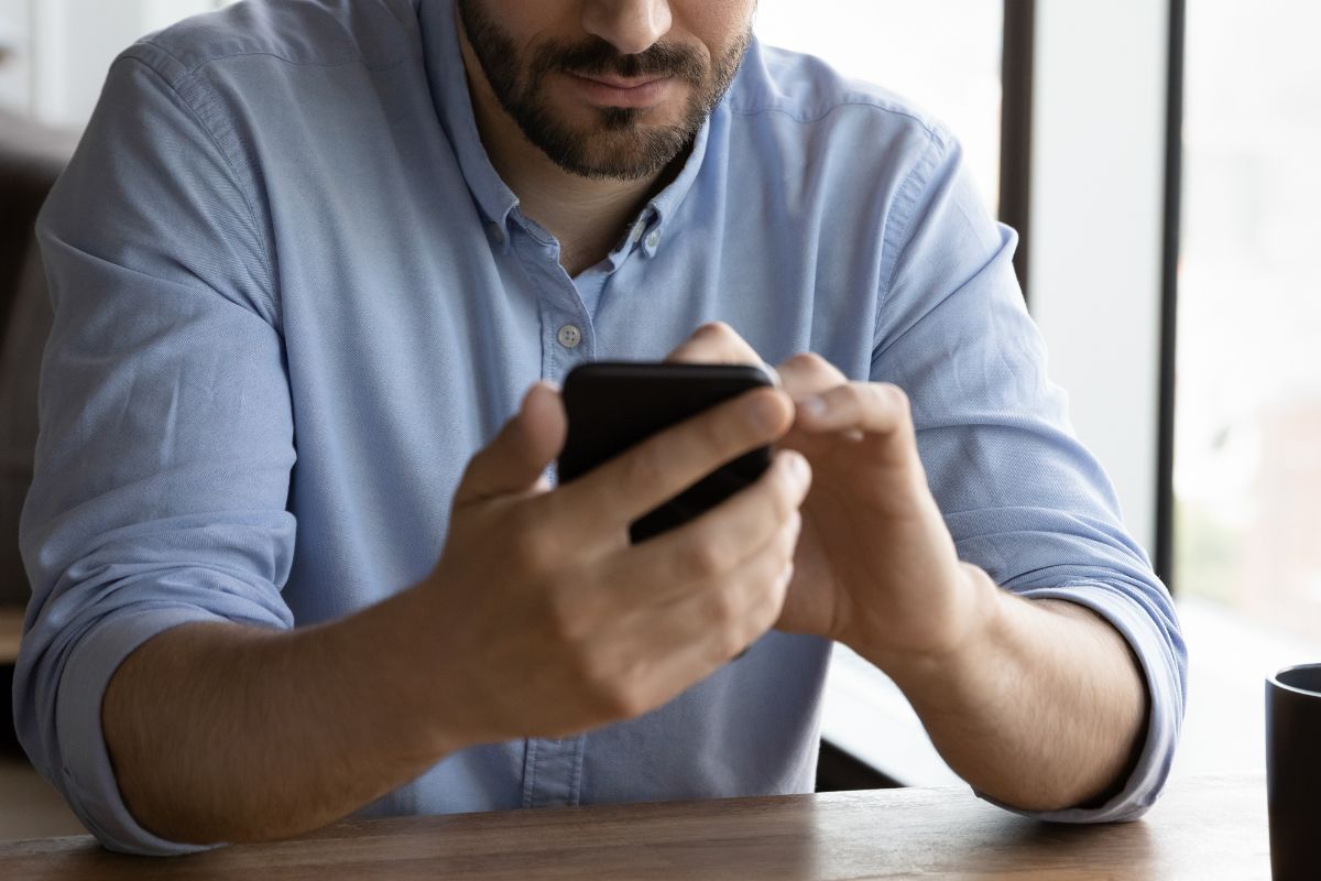 Foto colorida de um homem com o celular na mão - Metrópoles
