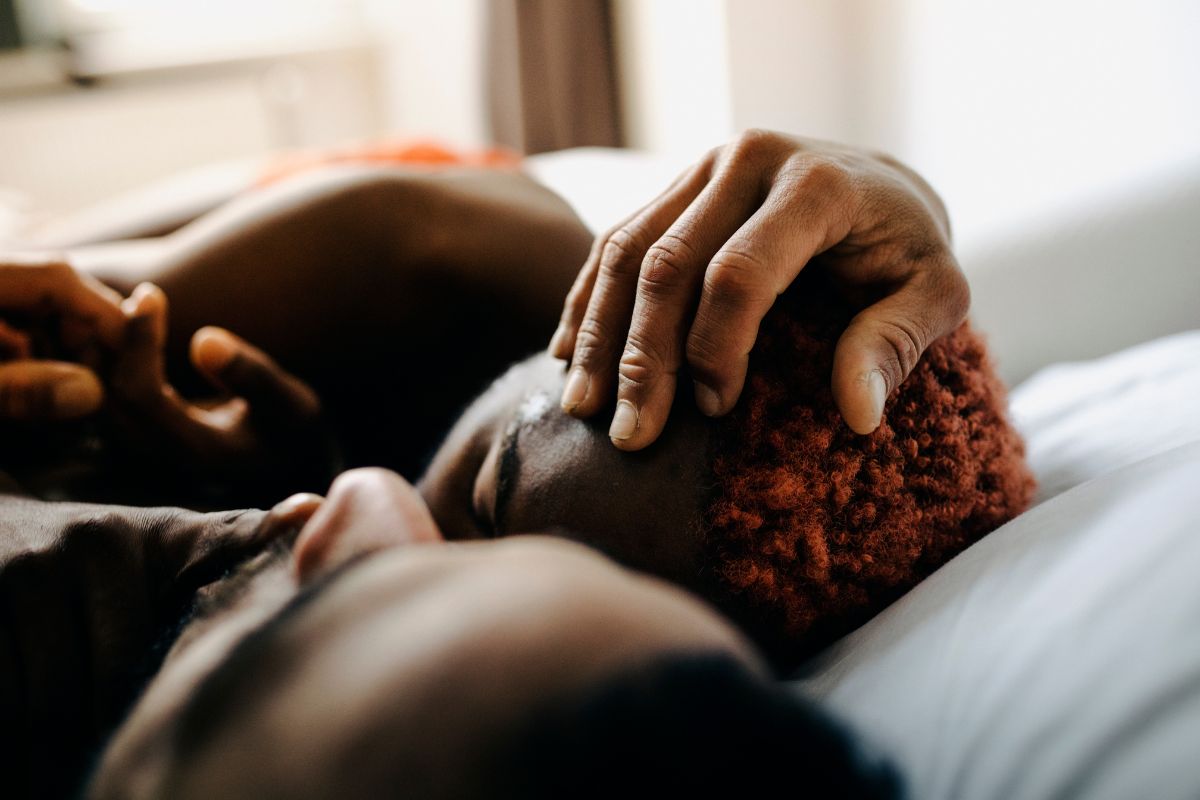 Foto colorida de um casal abraçado na cama - Metrópoles
