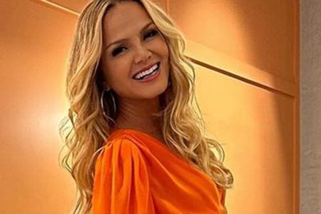 Eliana posa, sorridente, de cabelos soltos e look laranja - Metrópoles
