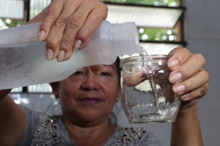 Foto colorida de mulher colocando água em copo - Metrópoles