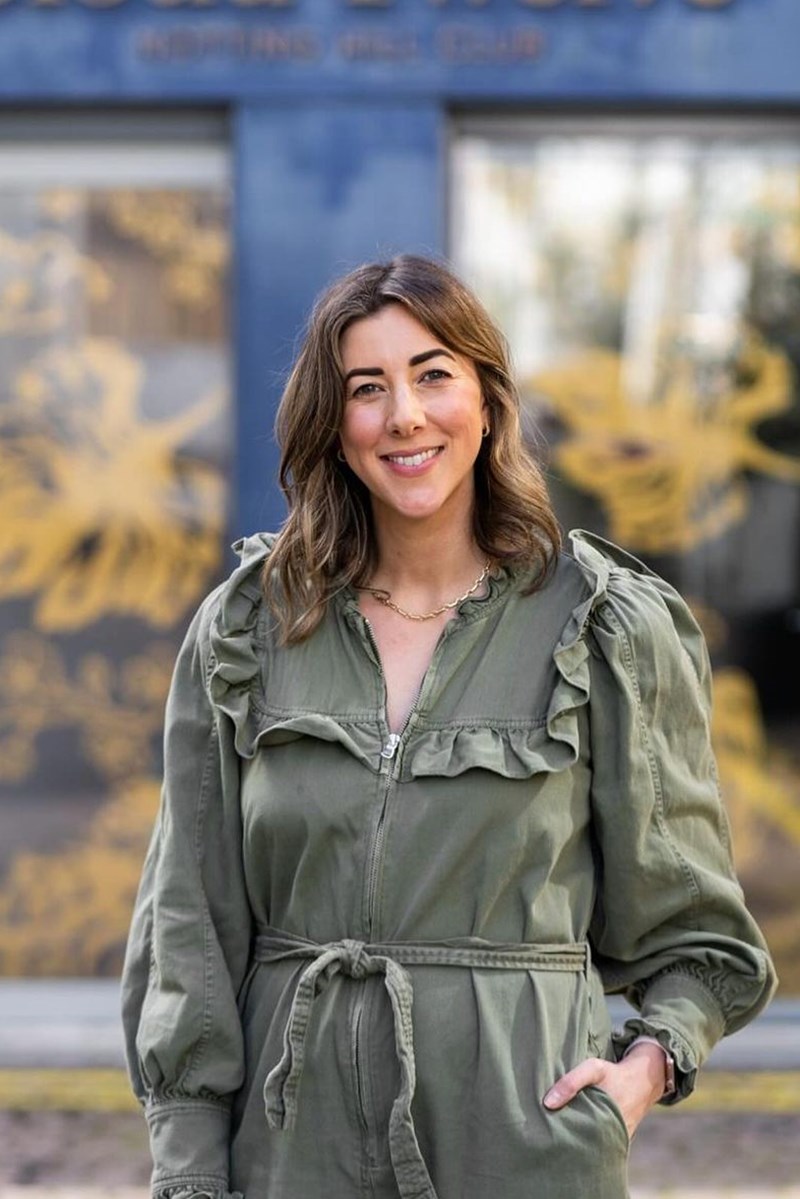 Foto colorida de mulher com cabelo castanho claro. Ela veste um macacão verde-militar - Metrópoles