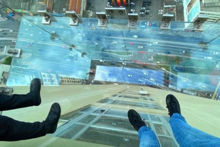 Imagem colorida mostra pessoas em elevador panorâmico - Metrópoles