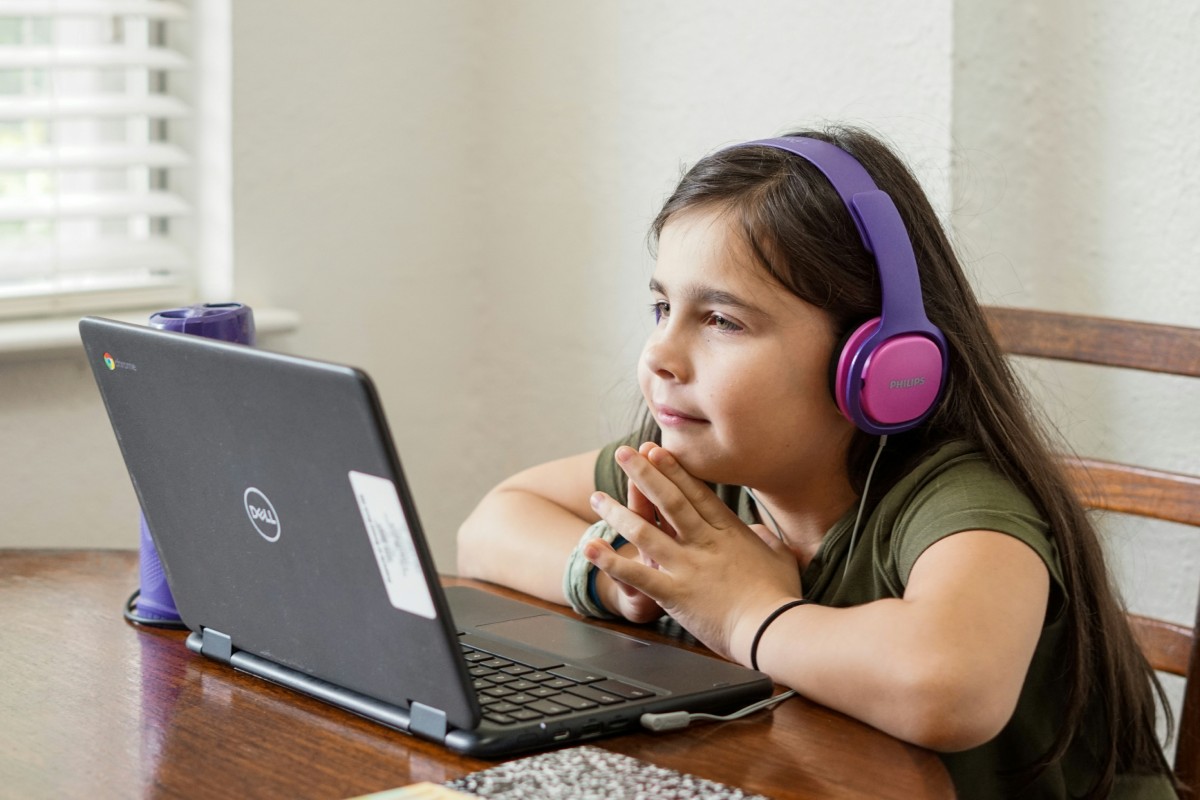 Fotografia colorida mostrando menina sentada em mesa estudando pelo computador-Metrópoles