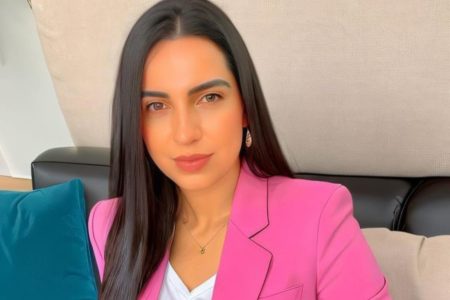 Mulher branca com cabelos castanhos lisos veste blazer rosa e camiseta branca - Metrópoles