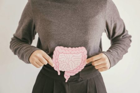 Foto mostra mulher segurando desenho de intestino diante de sua barriga