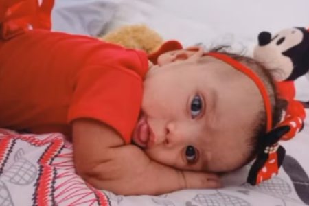 Foto colorida de bebê deitada, vestida com roupa vermelha - Metrópoles