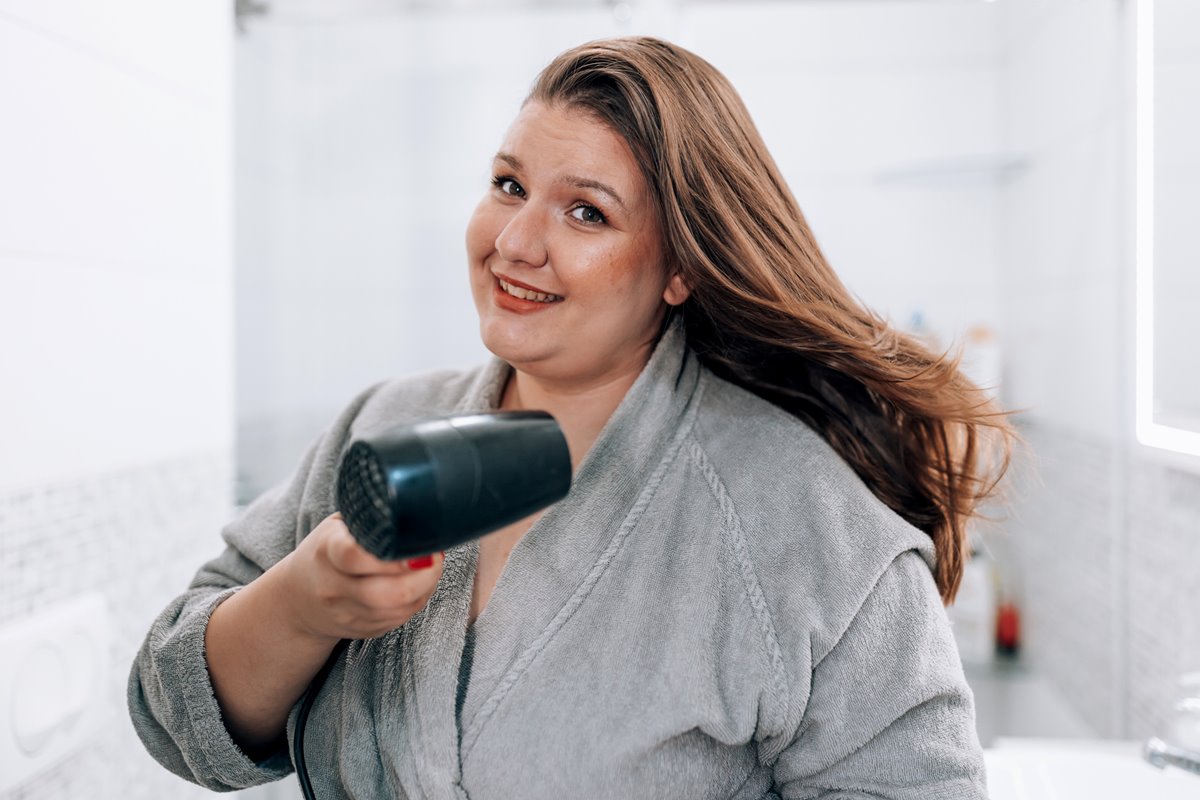 Foto colorida de mulher secando o cabelo - Metrópoles